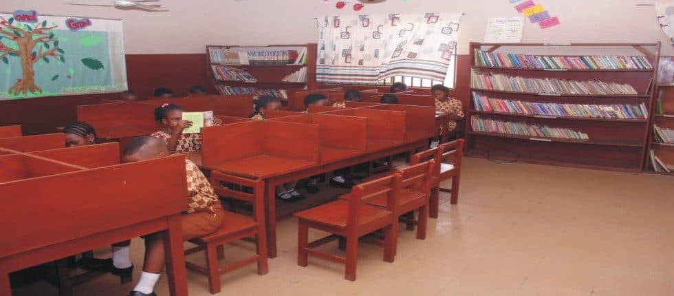 A room at B and B School lined with bookshelves, with wooden tables and chairs