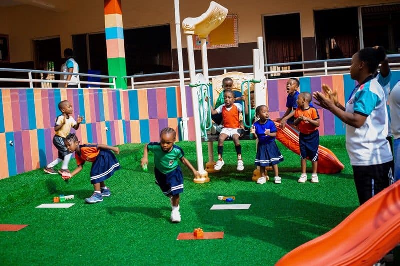Nursery children playing on the slide and soft play area in the B and B School playground