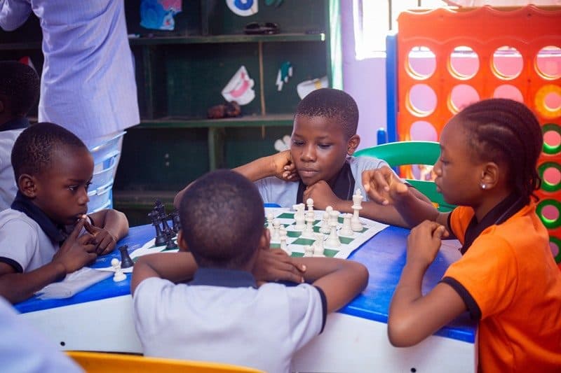 Pupils gathered around a table playing a board game in a B and B School classroom