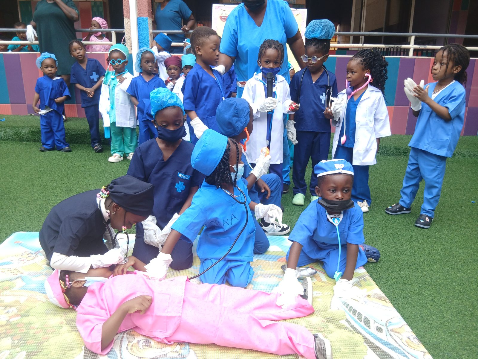 Nursery pupils dressed as doctors gathered around a classmate playing the patient on a mat